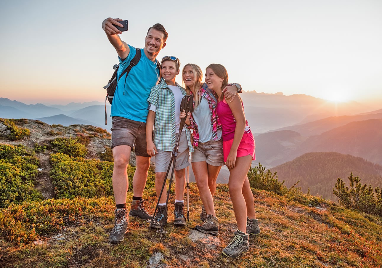 A group of hikers taking a selfie on a mountain during sunset
