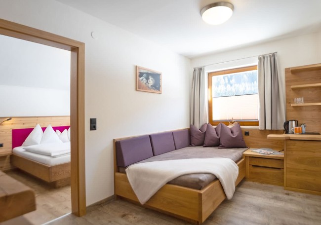 Cozy modern room with a bed, couch, window, and wooden furniture