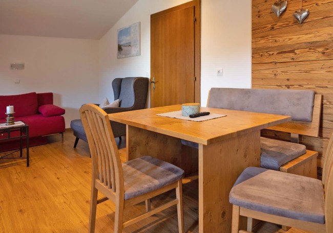 A cozy dining area with a wooden table, chairs, and a red sofa in a warmly lit room