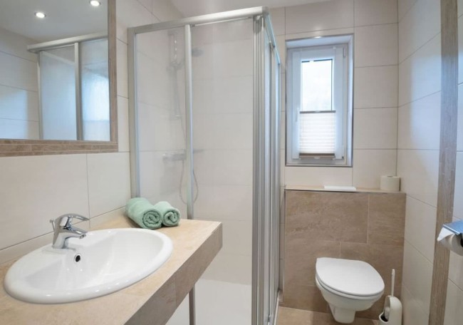 Compact bathroom with a shower, toilet, and sink, featuring minimalistic design