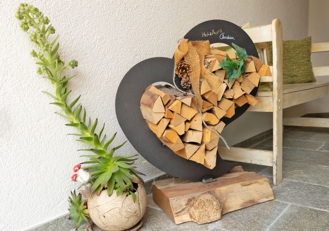 Decorative heart-shaped log stack with a potted plant beside a wooden bench
