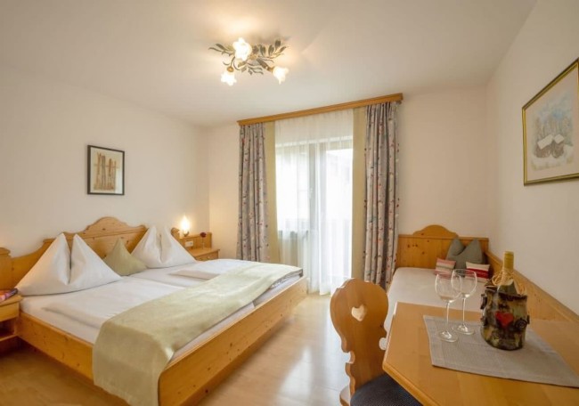 Cozy room with a double bed, wooden furniture, and a window with curtains