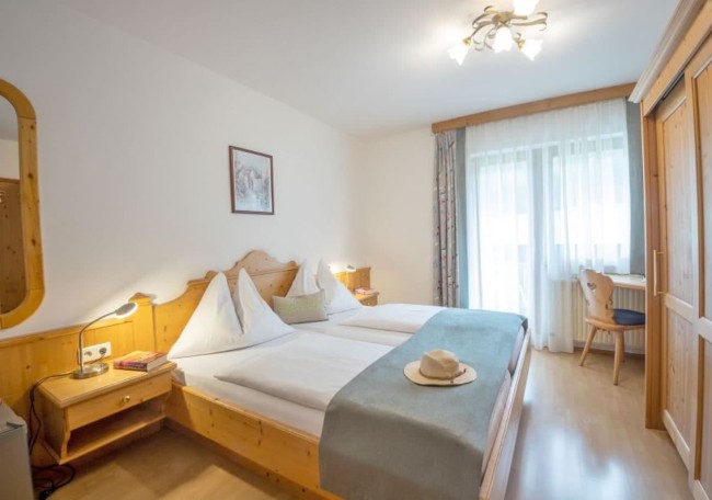 Bright room with twin beds, wooden furniture, and a hat on a teal bed runner