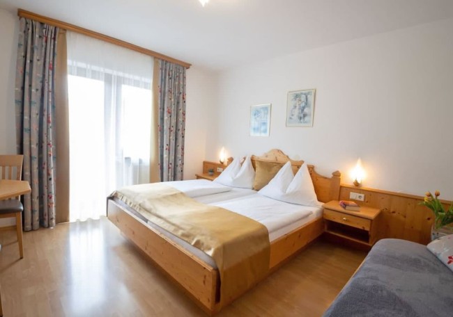 A cozy bedroom with a large bed, wooden furniture, and soft lighting