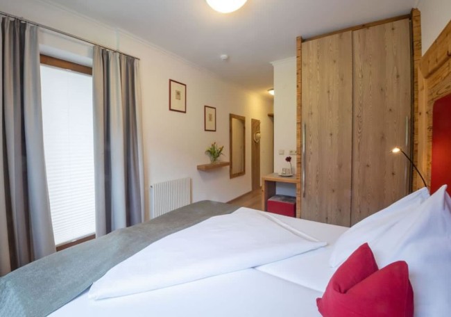 Bright room with a double bed, wooden wardrobe, and neatly arranged decor