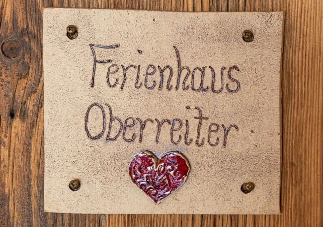 Sign reading "Ferienhaus Oberreiter" with a heart below, on wood