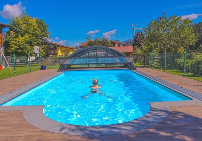 Person swimming in an outdoor pool with a retractable cover on a sunny day
