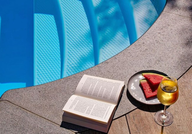 Book, watermelon, and wine near a pool
