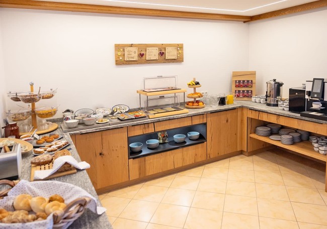 Breakfast buffet with various breads, fruits, cereals, and beverages in a cozy setting