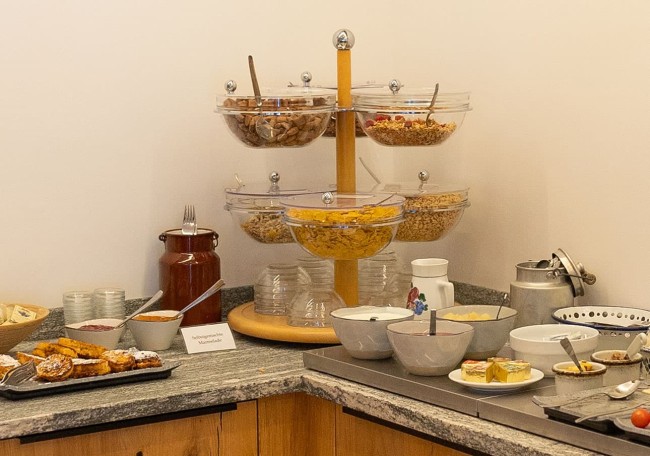 Breakfast buffet with cereals, pastries, and various food items on a counter