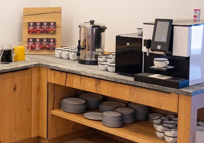 Coffee station with machines, cups, and plates on a wooden countertop