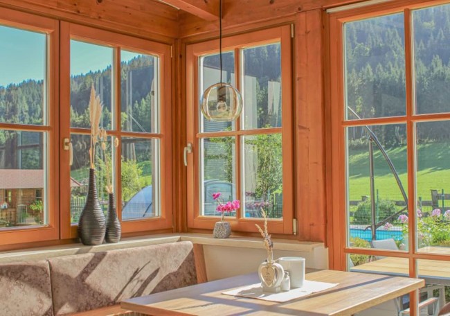 Sunny room with a wooden table and large windows overlooking a scenic landscape