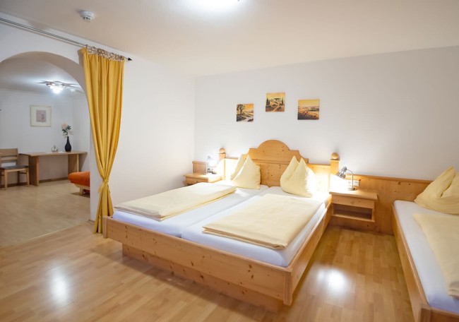 Bright bedroom with a wooden double bed, yellow linens, and a cozy seating area